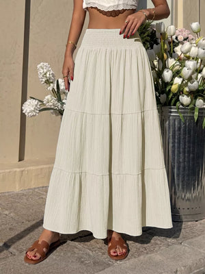 Smocked tiered maxi skirt in apricot with flowing fabric and textured detail.