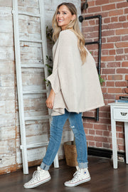 Cream knit sweater with relaxed cape sleeves and batwing sleeves.