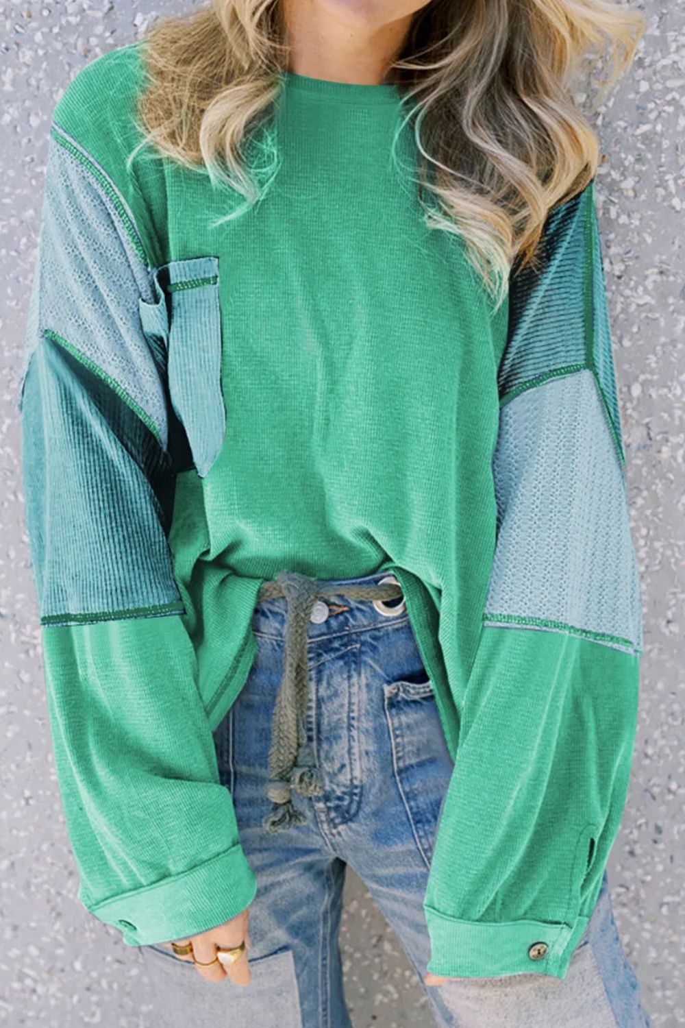 Green blouson top with waffle knit and colorblock sleeves, featuring a chest pocket.