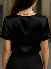 Black satin V-neck shirt with cuffed short sleeves and a pearl necklace.