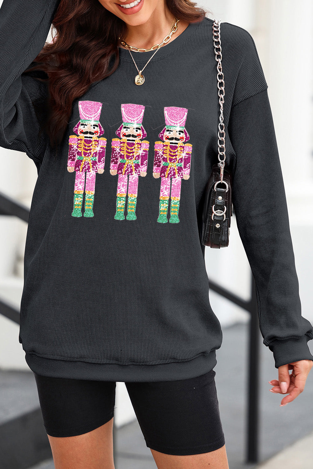 Black ribbed sweatshirt with three sequined nutcracker embellishments.