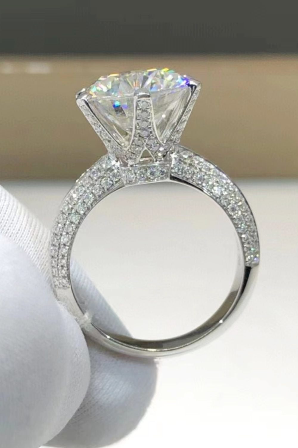 Silver pavé band moissanite solitaire ring with a large, brilliant-cut center stone.