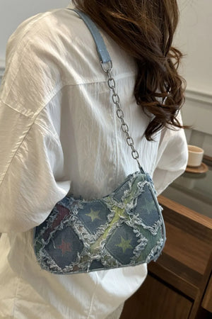 Denim shoulder bag with starburst pattern and frayed edges, light blue strap
