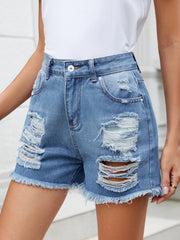 Distressed denim cutoff shorts in medium wash with raw hem and ripped details.