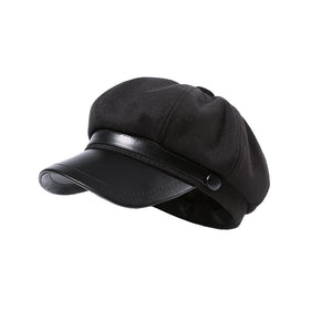 Black newsboy cap with faux-leather brim and button detail.