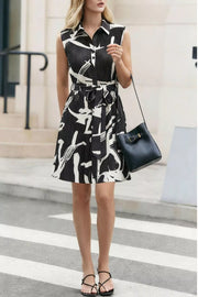 Chic abstract print a-line dress with belt, button front, and sleeveless design.