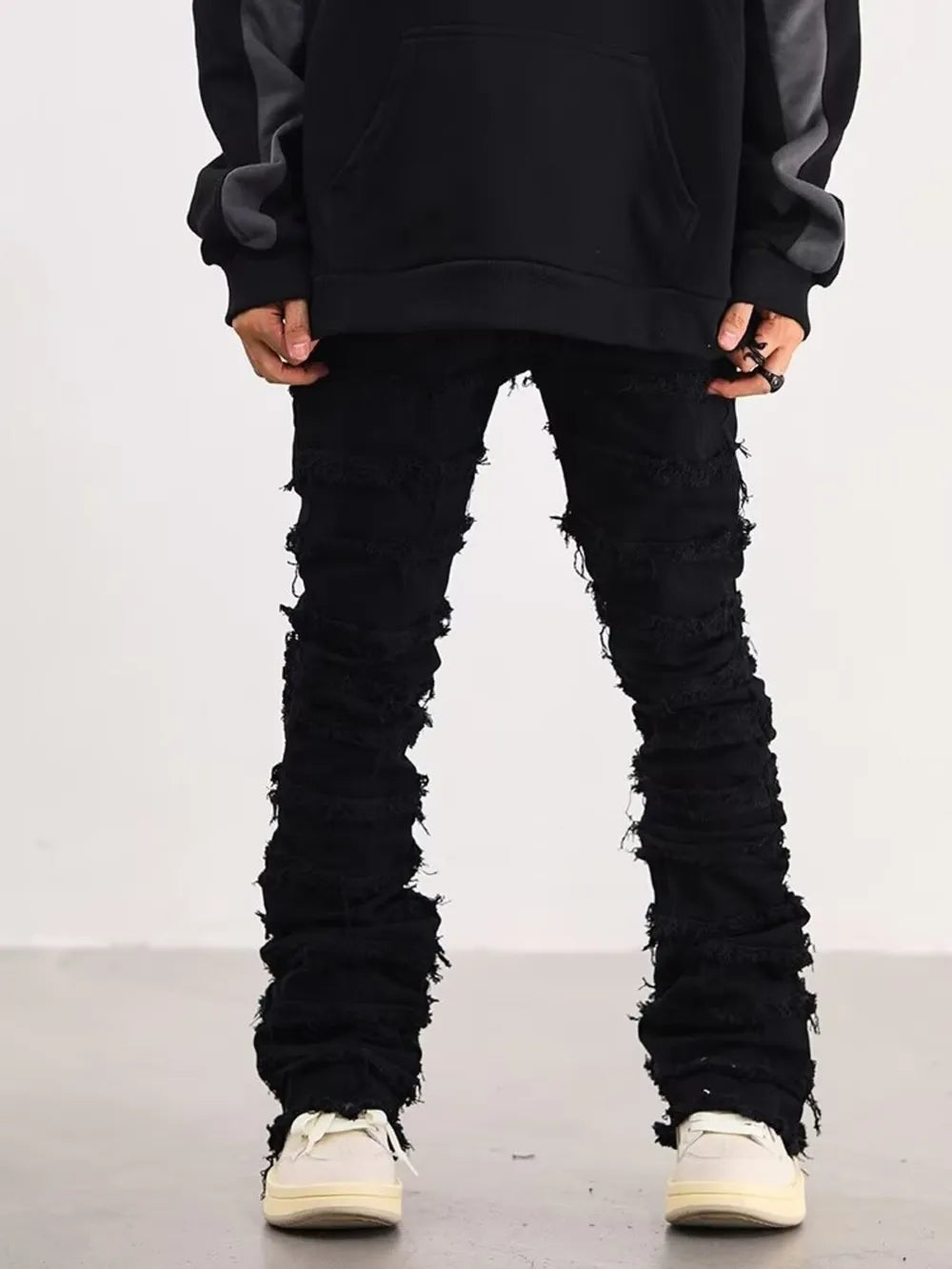 Black cotton jeans for men with frayed hem and stacked leg detail.