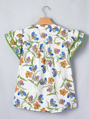 Cotton shirt with vibrant floral print, ruffled sleeves, and green trim.