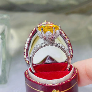 Yellow moissanite solitaire ring with diamond halo and band in a ring box.