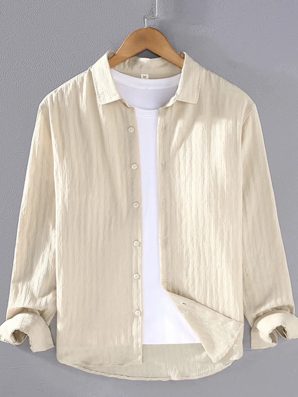 Textured long sleeve button-up shirt in apricot with classic collar, worn over a white t-shirt.