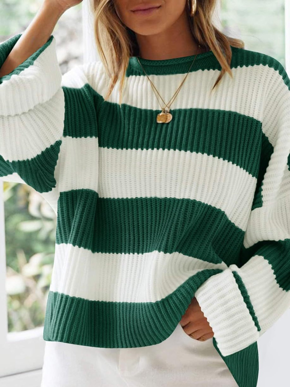 Striped oversized knit sweater in dark green and white with a crew neck and long sleeves.