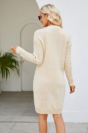 Cream cable knit bodycon mini dress with long sleeves and textured knit.