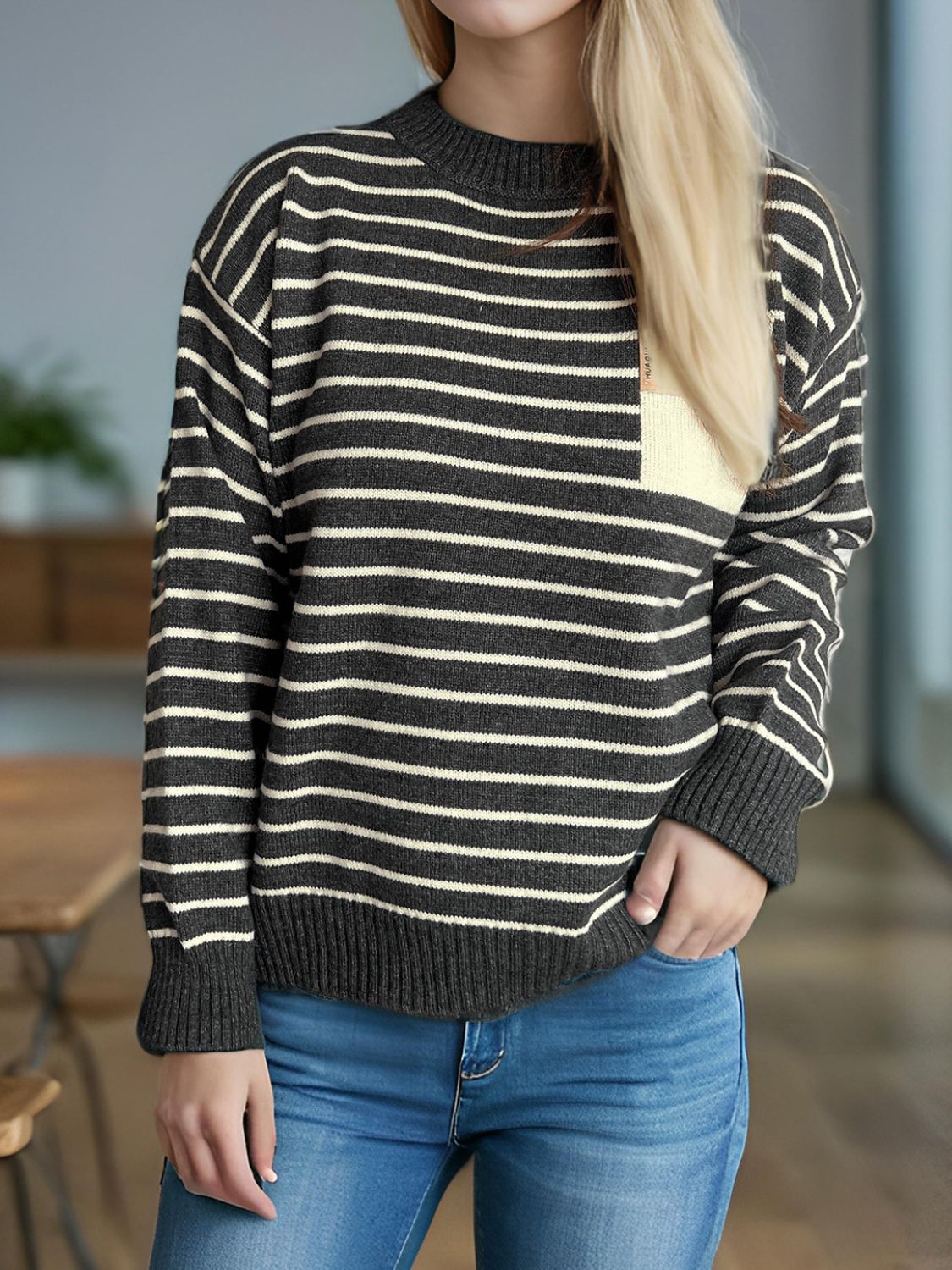 Asymmetrical stripe knit sweater in dark gray with cream pocket detail and crew neck.
