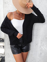 Black acrylic cardigan with textured sleeves and open front, styled with a white cami and black shorts.