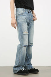 Distressed flare-leg denim jeans in medium wash with ripped knees and frayed hem.
