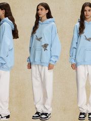 Light blue relaxed fit hoodie with embroidered birds and a front pocket.