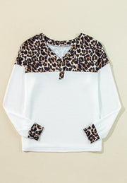 White waffle knit henley sweater with leopard print yoke and cuffs.
