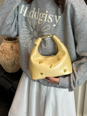 Pastel yellow mini hobo bag with gold accents and bone charms.