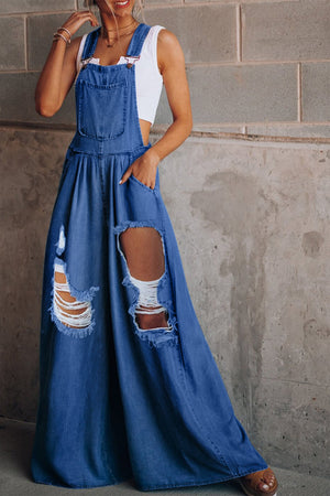 Distressed denim palazzo dungaree jumpsuit in light blue with wide legs and ripped details.