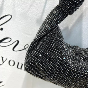 Black rhinestone crescent tote bag with twisted strap detail.