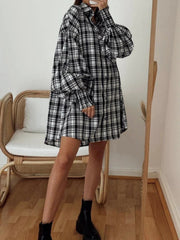 Black and white plaid oversized shirt with balloon sleeves and button front, styled with black boots.