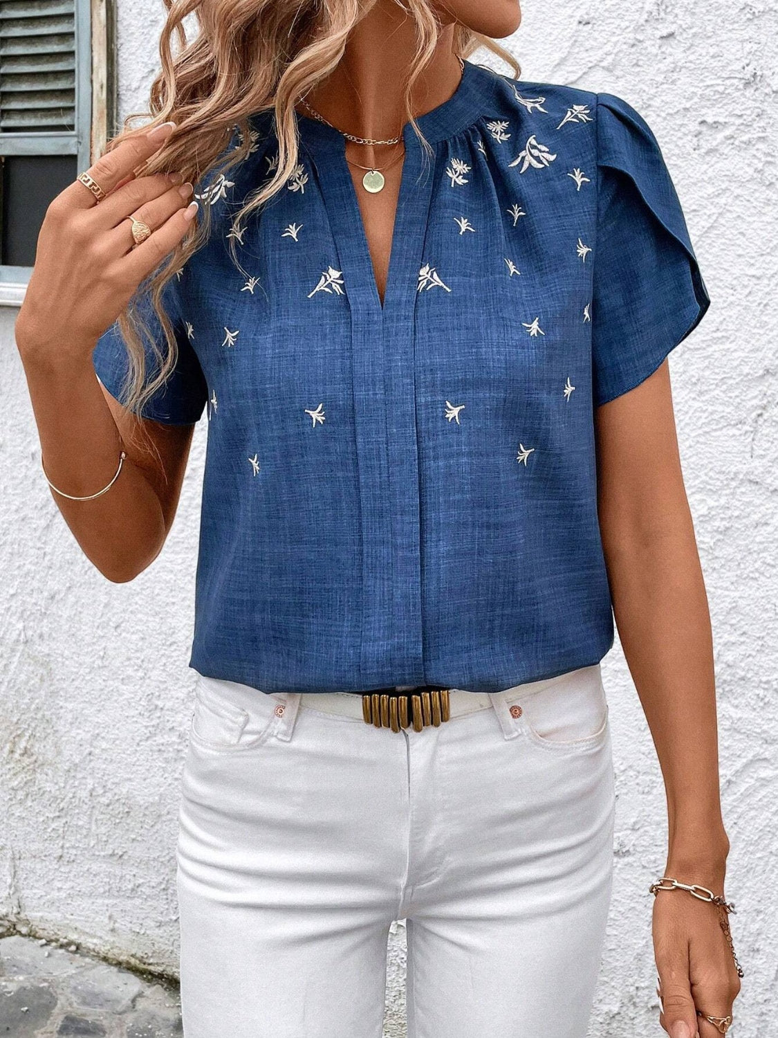Blue embroidered floral keyhole blouse with short flutter sleeves.