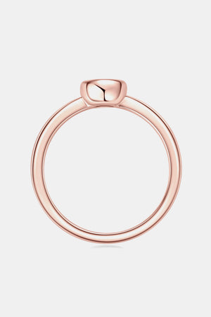 Rose gold solitaire bezel ring with a thin band.