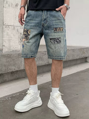 Men's blue denim shorts with graphic patchwork details and distressed accents.