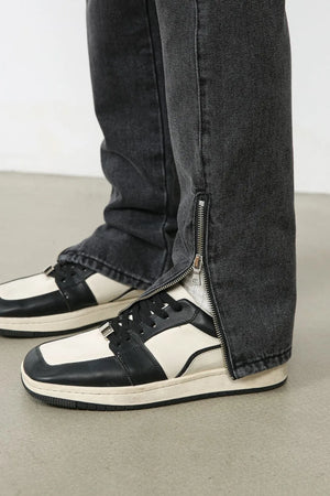 Dark washed denim trousers with a split hem zipper detail shown on the ankle.