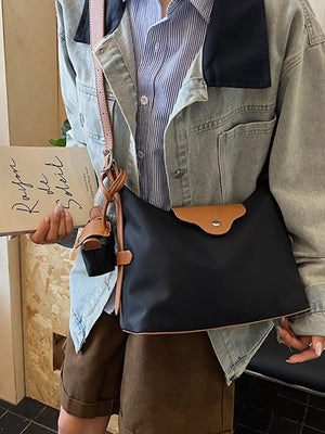 Black canvas hobo bag with coin purse and tan trim, worn crossbody.