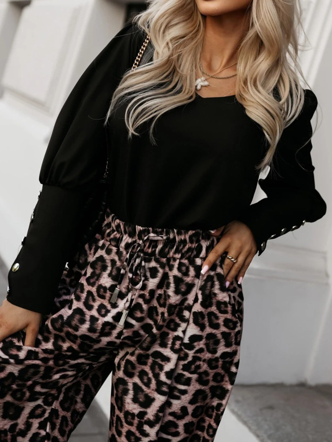 Black blouson sleeve top with button cuffs and V-neck, paired with leopard print pants.