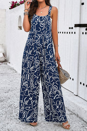 Dark blue wide leg jumpsuit with abstract white print, square neck and button straps.