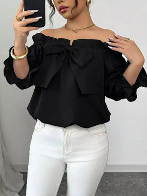 Black off-the-shoulder blouse with ruffled bow detail and puff sleeves.