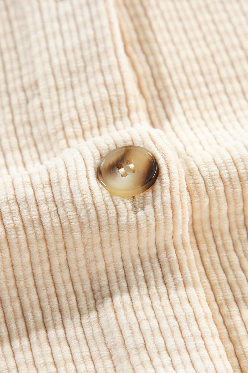 Beige corduroy utility jacket with textured fabric and a tortoiseshell button detail.