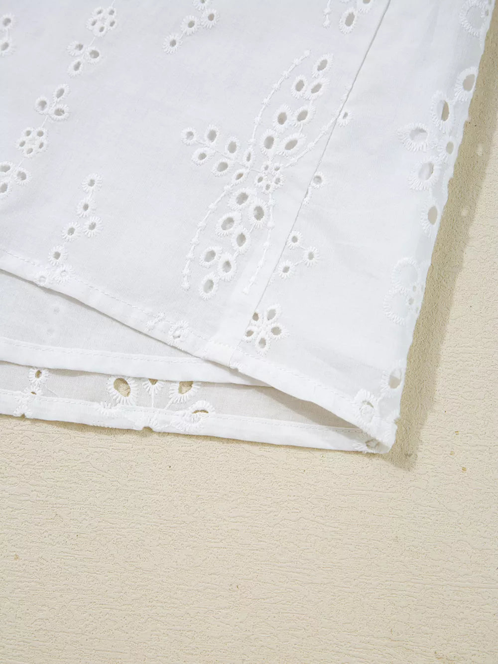 White cotton maternity blouse with delicate eyelet embroidery and ruffled details.
