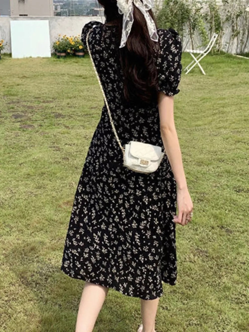 Black botanical print midi dress with puff sleeves and a-line skirt.