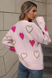 Pink knit crewneck sweater with scattered white and hot pink heart motifs.