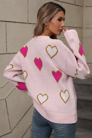Pink knit crewneck sweater with scattered white and hot pink heart motifs.