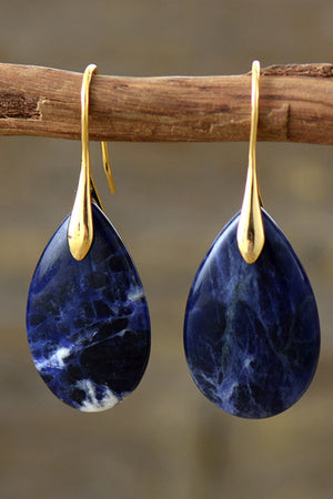 Gold dangle earrings with teardrop sapphire stones and white marbling.
