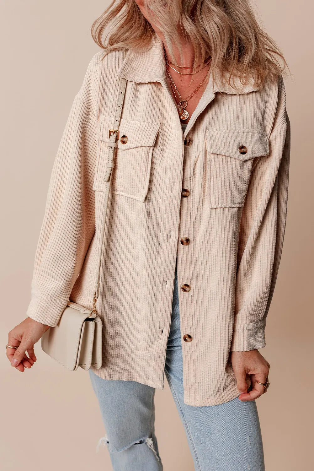 Beige corduroy oversized utility jacket with button-flap chest pockets and a relaxed fit.