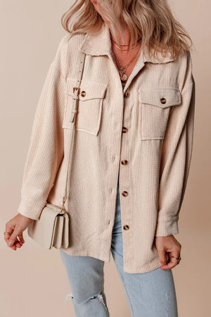 Beige corduroy oversized utility jacket with button-flap chest pockets and a relaxed fit.