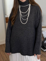 Flared sleeve ribbed turtleneck sweater in Floral Gray acrylic, styled with layered pearl necklaces.