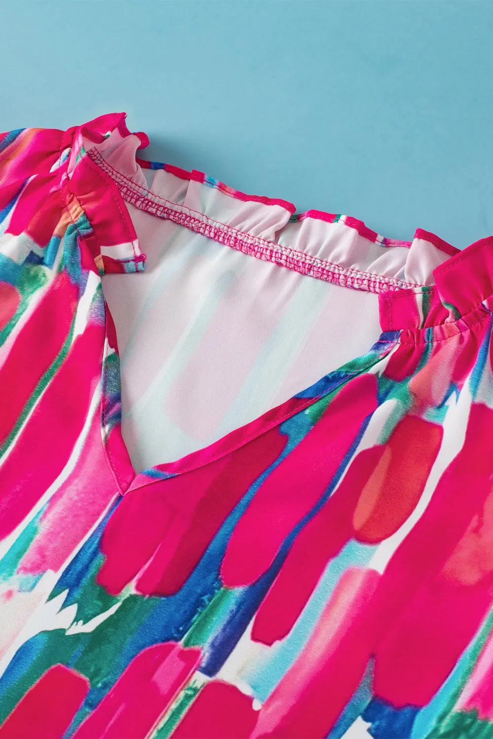 Brushstroke ruffle sleeve V-neck top in hot pink with abstract print and ruffled neckline detail.