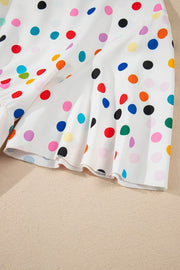 White polka dot blouse with tiered flutter sleeves and ruffled hem detail.