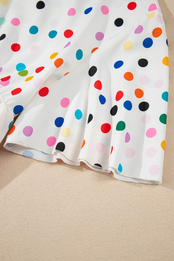White polka dot blouse with tiered flutter sleeves and ruffled hem detail.
