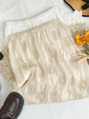 Apricot midi skirt with crochet floral details and elastic waist, shown with white skirt.