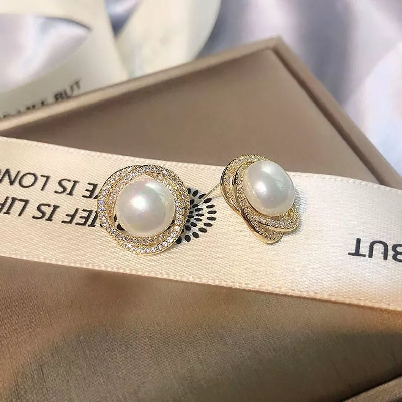 Elegant pearl and zircon stud earrings in gold with a circular halo design.