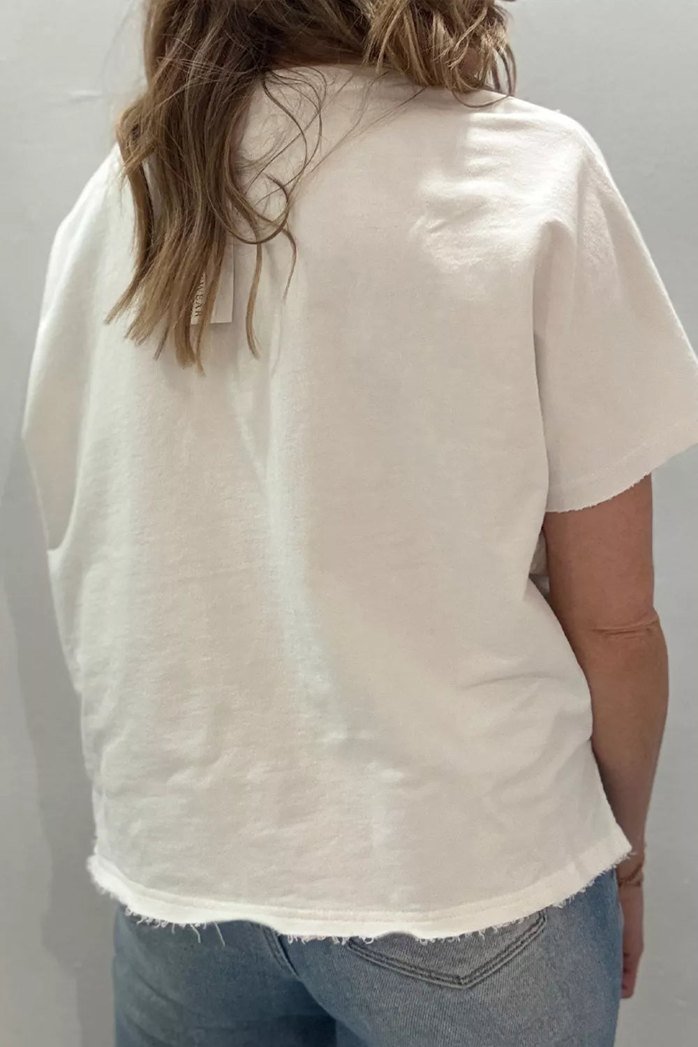 White cotton tee with frayed hem and short sleeves.