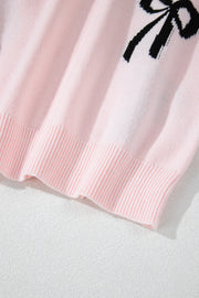 Blush pink knit crewneck sweater with black bow motif detail and ribbed hem.