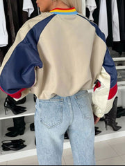 Beige cropped bomber jacket with colorblock sleeves and striped collar.